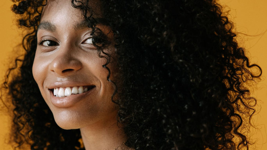 Young African American woman with natural curls using Sunny Isle's Batana Curling Crème